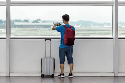 Rear view of man standing by window