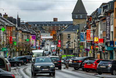 Cars on city street by buildings against sky