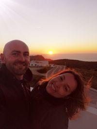 Portrait of smiling man and woman against sky during sunset