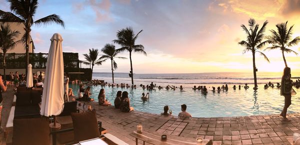 Group of people by swimming pool at sunset