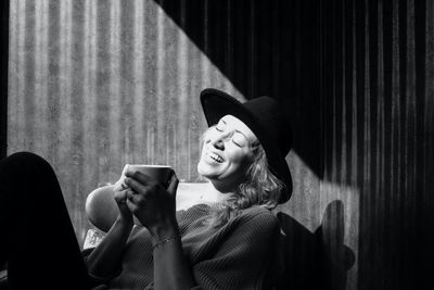 Woman sat laughing whilst drinking coffee in a cafe