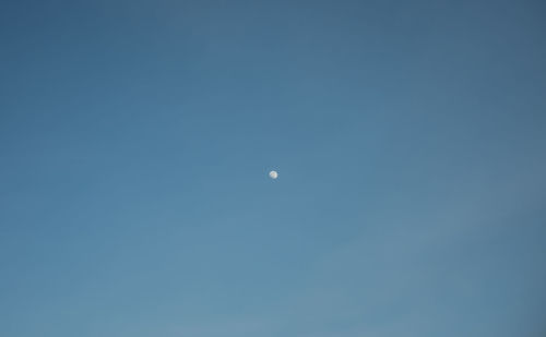 Low angle view of moon against clear blue sky