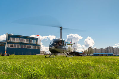 A small commercial helicopter parked on a helipad with rotating propellers