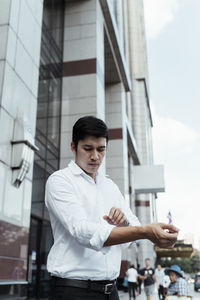 Portrait of young man standing against built structure