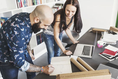 Happy male and female architects working at table