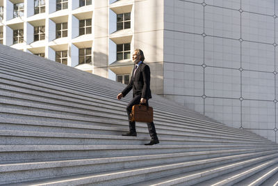 Mature businessman with bag moving up on staircase