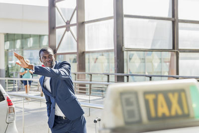 Young businessman with arm raised hailing taxi