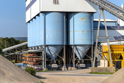 Big blue metallic industrial silos for the production of cement at an industrial cement plant.
