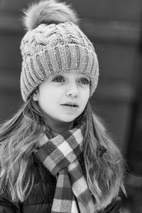 Cute girl looking away wearing knit hat standing outdoors during winter