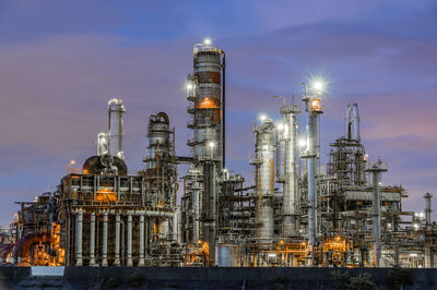 Low angle view of illuminated factory against sky at night