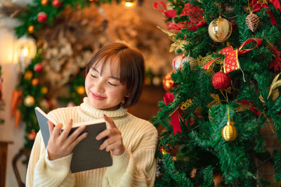 Portrait of smiling woman holding christmas tree