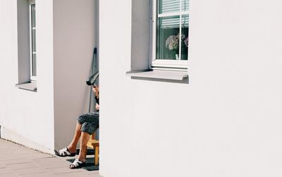 Low section of man with hair dryer sitting by houses