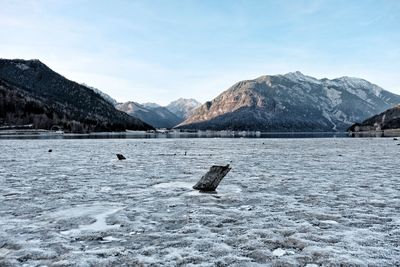 Scenic view of frozen lake by mountains against sky