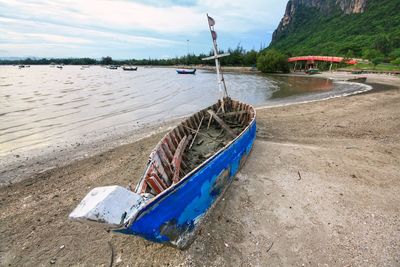 Boat moored on beach against sky