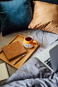 Cozy home, autumn warm mood. laptop, notebook and cup of tea at tray on blanket in bed in the