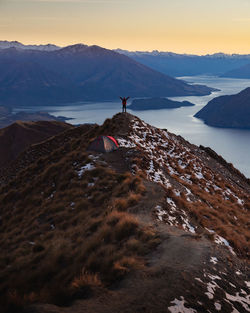 Rear view of man standing on mountain during sunset