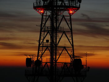 Low angle view of silhouette cranes against sky during sunset