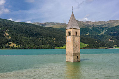 Cross on building by mountains against sky