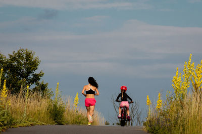 Rear view of women with umbrella against sky