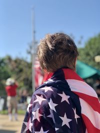 Rear view of boy and woman against sky with flag