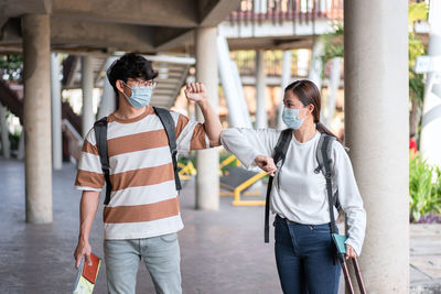 Couple wearing mask doing elbow bump outdoors