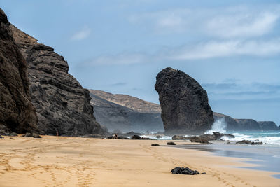 Rock formations on beach against sky