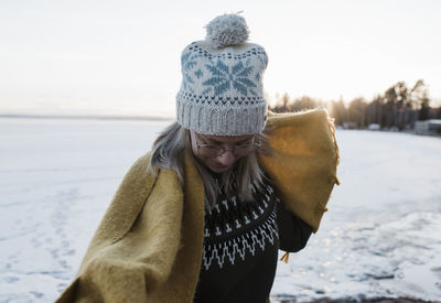 Midsection of woman wearing hat standing in snow