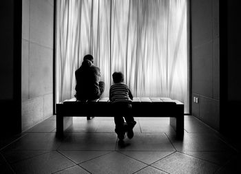 Rear view of siblings sitting in corridor