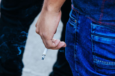 Midsection of man holding cigarette