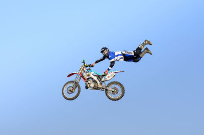 Low angle view of man riding motorcycle against clear sky