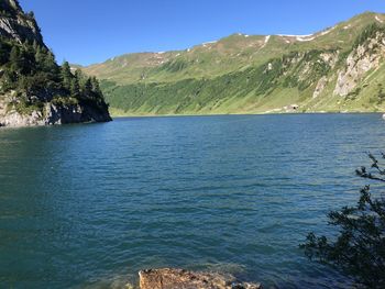 Scenic view of sea and mountains against clear blue sky