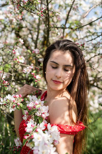 Young caucasian woman enjoying the flowering of an apple trees, walking in spring apple gardens