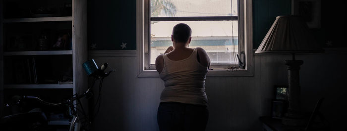 Full length of man looking through window at home