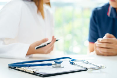 Midsection of woman holding smart phone on table