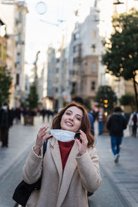 Portrait of smiling young woman standing on city street