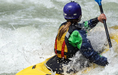 Rear view of woman kayaking in river