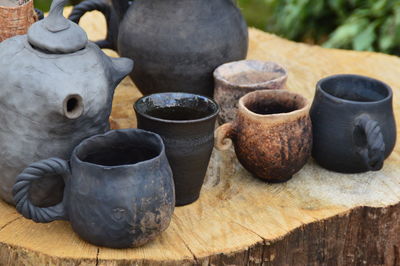 Close-up of pots and cups on tree stump