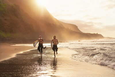 People on beach against sky during sunset