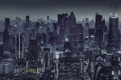 Aerial view of illuminated buildings in city against sky at dusk