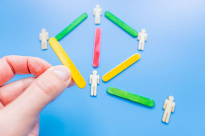 Close-up of hand holding toy against blue background