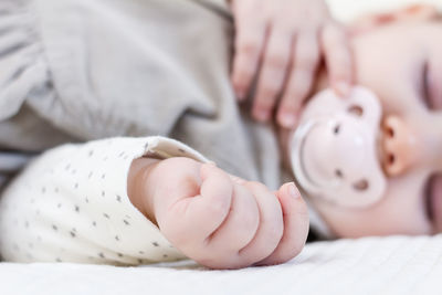 Low section of baby lying on bed