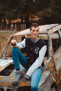 Portrait of young man sitting on car