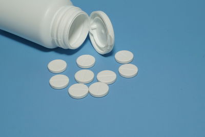 Pills with container on blue background