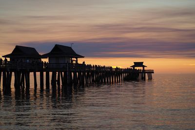 Silhouette house by sea against sky during sunset