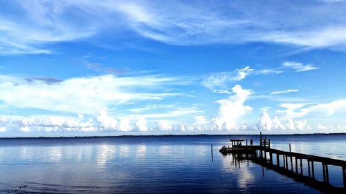 Pier on sea against cloudy sky