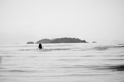 Person on sea against clear sky