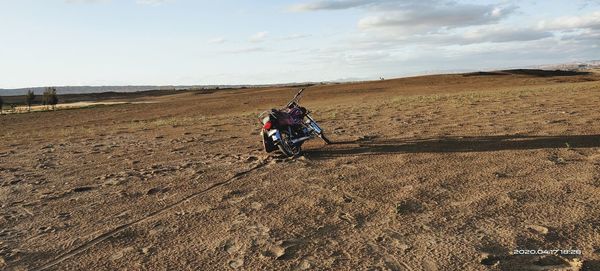 Man riding motorcycle on field against sky