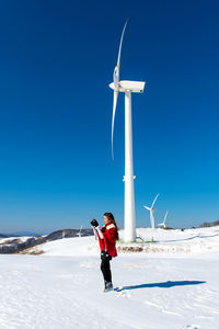 Full length of boy standing on field against clear blue sky