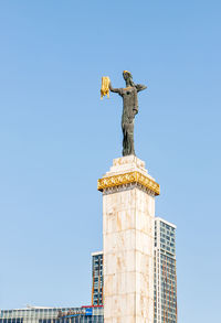 Low angle view of statue against building against clear sky