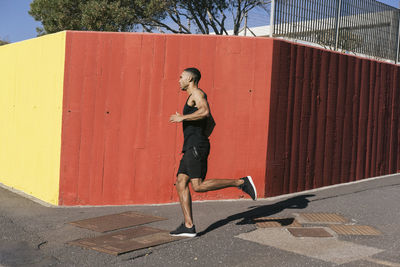 Full length of african american runner running against colorful wall person